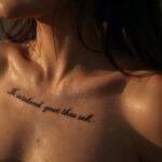 Tatuagem feminina na costela com uma frase escrita em fonte cursiva fina e delicada.