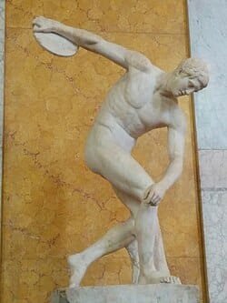 Discóbolo, escultura clássica grega reproduzida em mármore pelos romanos, exemplo icônico da arte clássica greco-romana